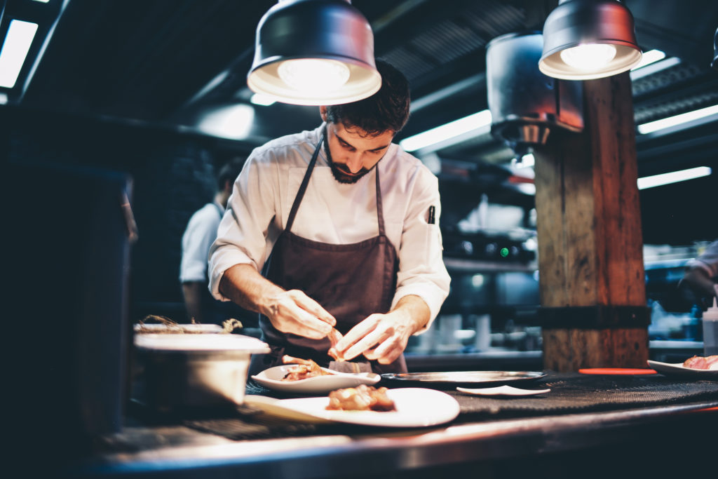 Chef serving food on a plate in the kitchen of a restaurant