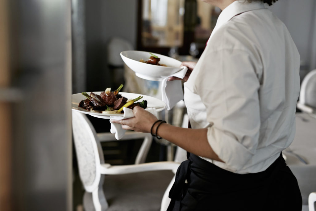 Waitress carrying two dishes in a restaurant
